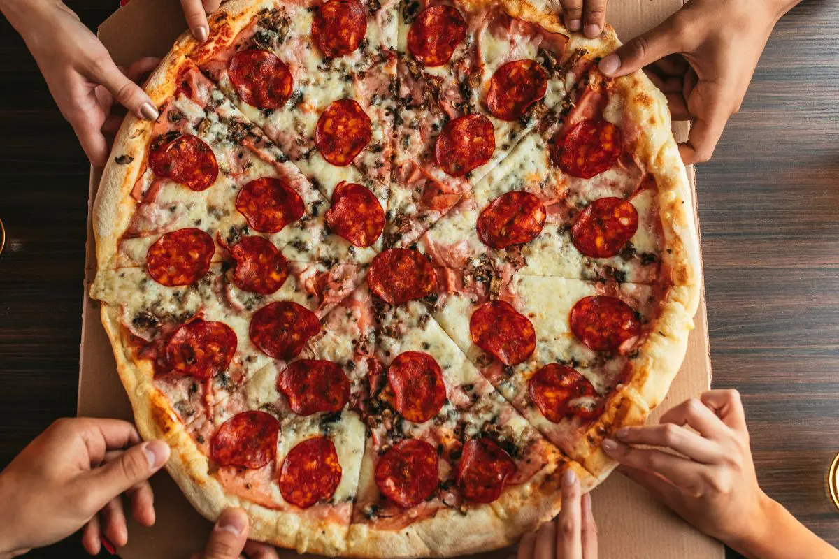 Hands grabbing pizza