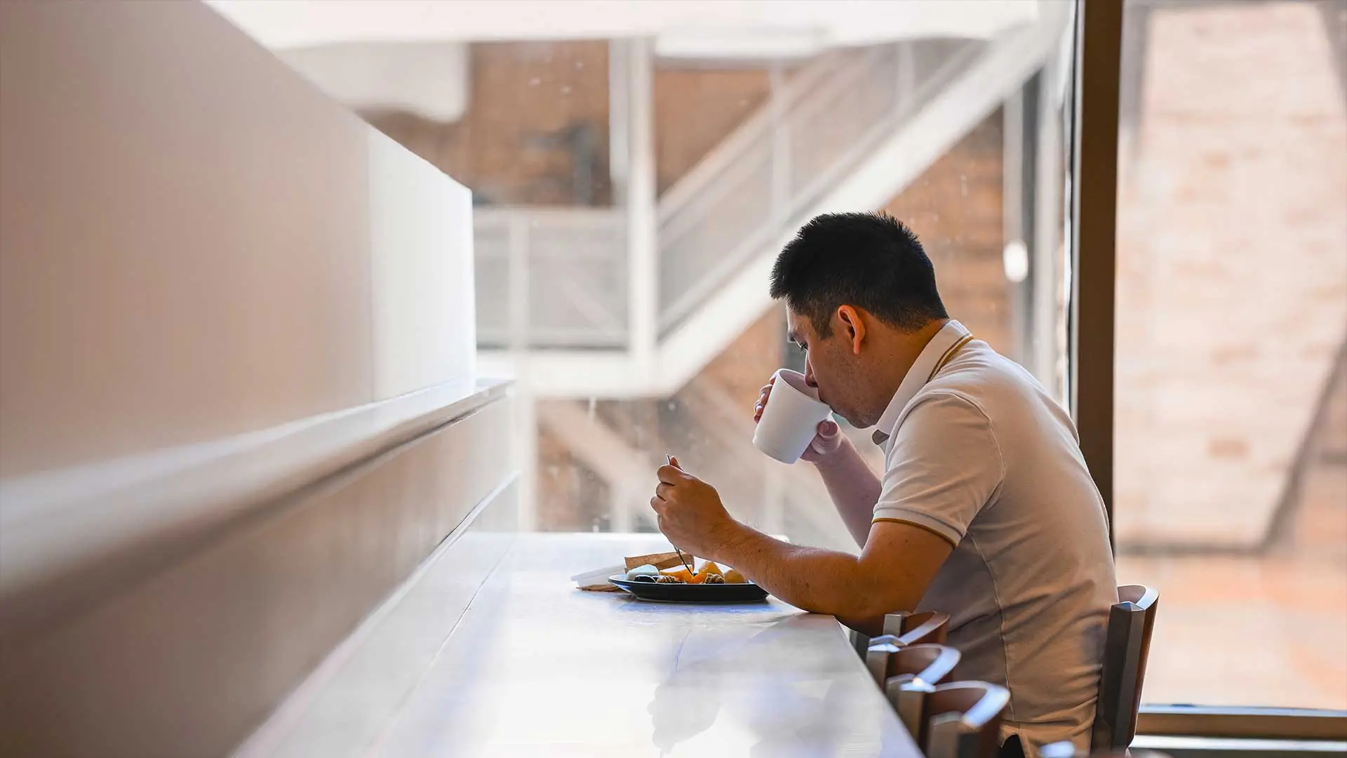 Two students holding dishes and smiling while standing in cafeteria